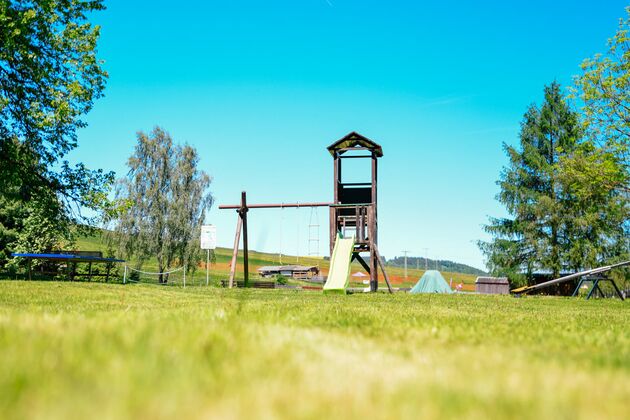 Spielplatz mit Kletterturm, Rutsche und Schaukel auf der Wiese