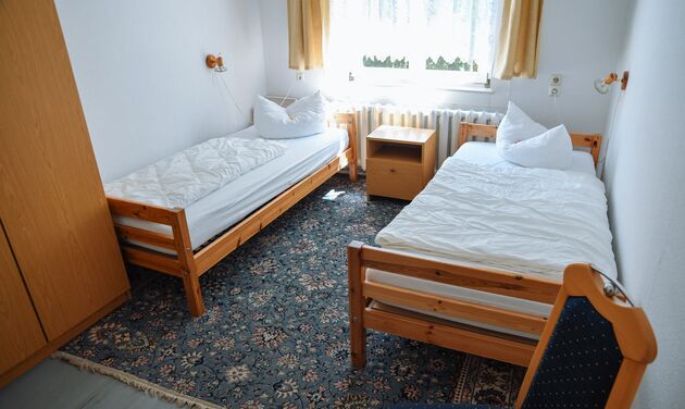 Doppelzimmer mit zwei Einzelbetten aus Holz und blauem Teppich