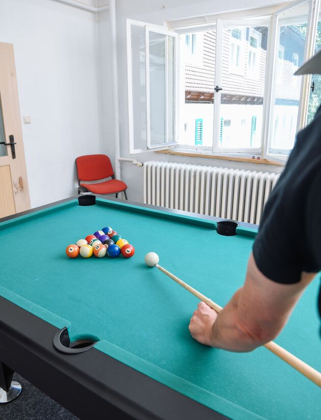 Billardtisch mit aufgebauten Kugeln und einem Spieler mit Queue