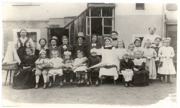 Gruppenbild von Kindern in Festkleidung mit Betreuerinnen vor dem alten Bethlehemstift
