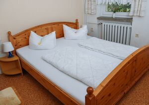 Doppelzimmer mit Doppelbett aus Kiefernholz und Nachttisch