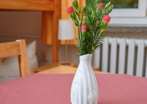 Weiße Vase mit Nelken auf dem Tisch im Einzelzimmer